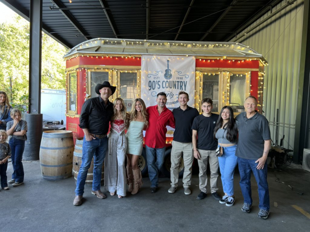 Group photo before a concert his son Pete performed at. A group of country singers and family in front of a trolly.