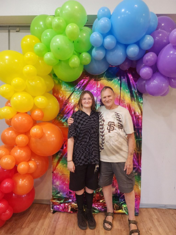 Celebrating with his granddaughter Rheanna. Balloons arch over Laren and Rheanna who pose for a photo.