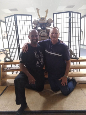 With son Andrew at his dojo. Inside shot of Andrew who's bald, and Laren both who are kneeling.