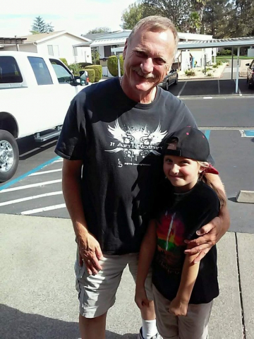 Laren with granddaughter Rheanna. Outside photo, Laren wearing his son's merch, with young granddaughter.